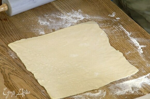 Слоеное тесто предварительно разморозить, затем раскатать на слегка присыпанной мукой рабочей поверхности в тонкие пласты.