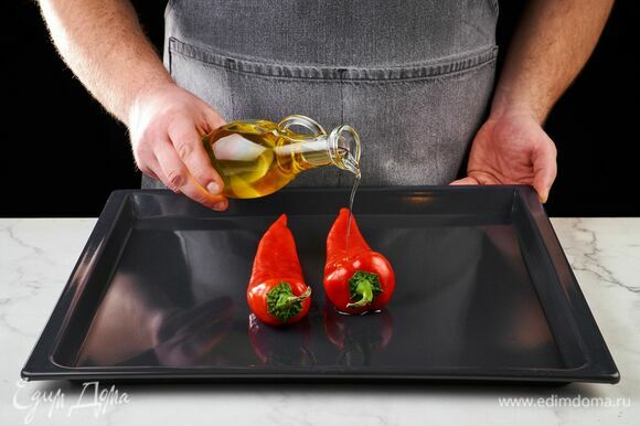 Перцы выложите на противень, полейте оливковым маслом и запекайте 15 минут в духовке, разогретой до 200°C. С запеченных перцев снимите кожуру.
