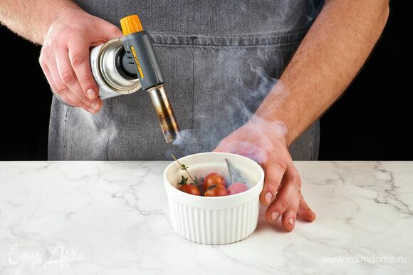 В огнеупорную емкость сложите тимьян, розмарин и помидоры черри. При помощи горелки опалите зелень, накройте емкость крышкой или фольгой.