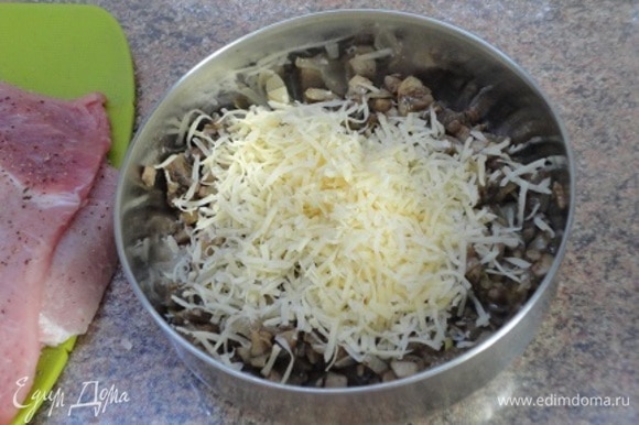 К остывшим грибам добавить натертый на мелкой терке сыр и перемешать.