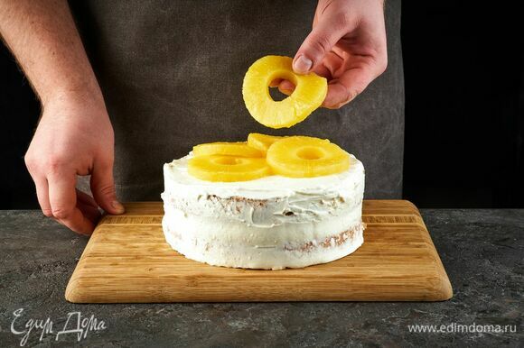 Соберите торт и сверху тоже смажьте кремом. Выложите кольца ананаса.
