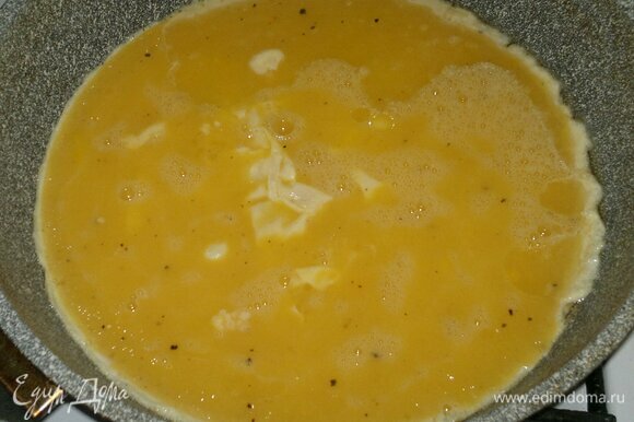В другой сковороде разогреть оставшееся растительное масло. Вылить в сковороду взбитые яйца. Подождать, пока схватятся низ и бока омлета.