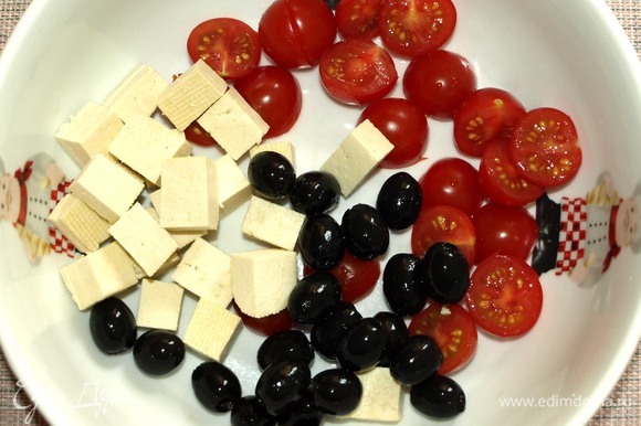 Все овощи хорошо промыть. В миску добавить помидоры черри, нарезанные половинками, тофу, нарезанный кубиками, маслины.