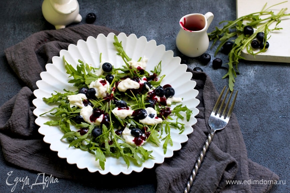 Выложите листья руколы в салатницу, добавьте чернику и сыр. Полейте салат ягодным соусом.