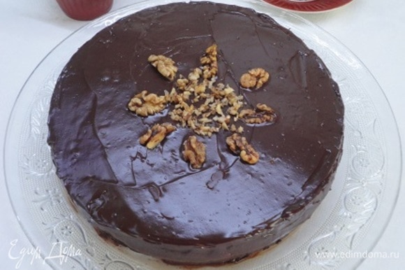 Растопите шоколад со сливочным маслом в микроволновой печи и полейте торт шоколадом. Украсьте грецкими орехами.