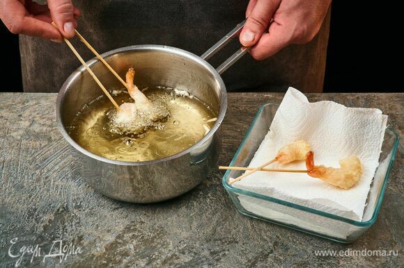 Доведите до кипения растительное масло в сковороде или сотейнике. Опустите креветки в кляре в масло. Обжаривайте со всех сторон до румяной корочки около минуты. Готовые жареные креветки выложите на бумажное полотенце, чтобы удалить остатки масла.