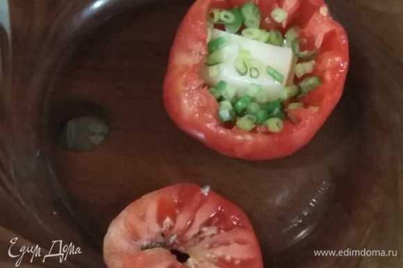 На дно томата положить кусочек сыра, посыпать щепоткой зеленого лука.