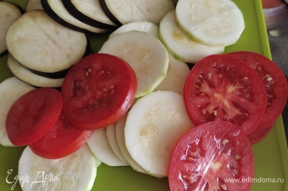 Кабачки, баклажаны и помидоры — колечками одинаковой толщины. Удобнее всего это сделать с помощью терки-овощерезки, но если такой нет, нарежьте просто ножом!