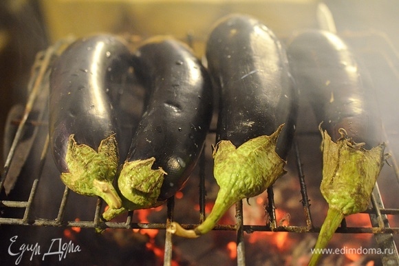 Баклажаны вымойте, наколите в нескольких местах вилкой и запеките на мангале или в духовке. Лучше на огне — это придаст блюду легкий аромат дымка.