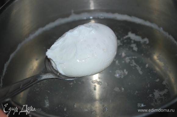 В небольшое количество кипящей воды налейте немного уксуса и аккуратно вылейте яйцо. Убавьте огонь и варите около 2 минут, затем шумовкой достаньте яйцо и выложите на салат. Сварите второе яйцо.