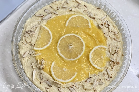 Форму смазать маслом, припудрить мукой. Выложить тесто. Сверху и посередине — лимонный крем. На крем уложить тонкие ломтики лимона и посыпать миндалем. Выпекать около 40 минут при 180°C.