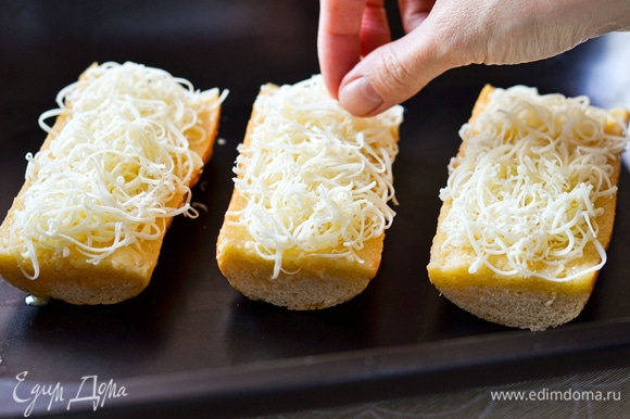 Сыр натереть на мелкой терке, распределить почти весь сыр по багету.