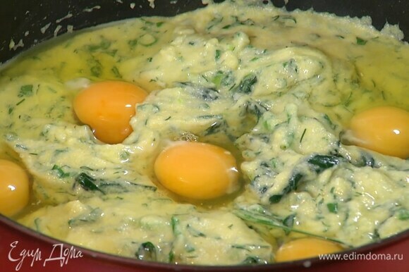 Нарубленную зелень и пармезан добавить в сковороду и все перемешать, затем сделать в поленте небольшие углубления и разбить в них яйца.