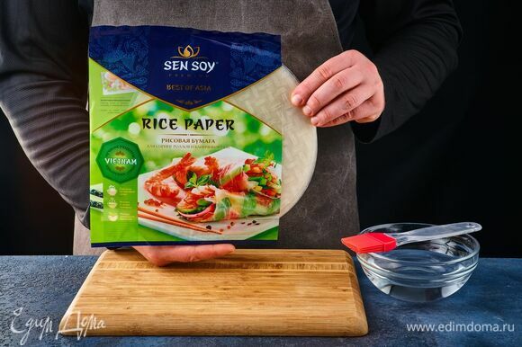 В посуду налейте теплую воду. Возьмите рисовую бумагу Sen Soy, намочите слегка водой с помощью кулинарной кисти или сбрызните пульверизатором.