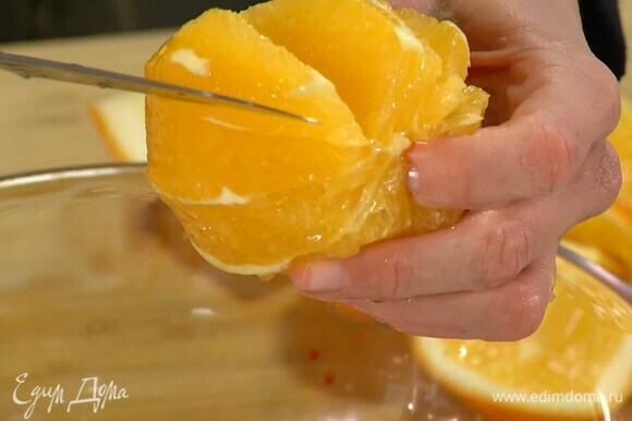 С апельсина срезать корки и над миской с салатом вырезать из перепонок мякоть.