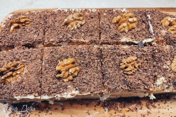 Разрезать готовый десерт на порции, посыпать тертым шоколадом и украсить грецким орехом.