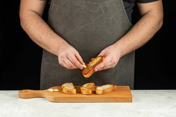 Каждый ломтик хлеба натрите разрезанным пополам зубчиком чеснока.