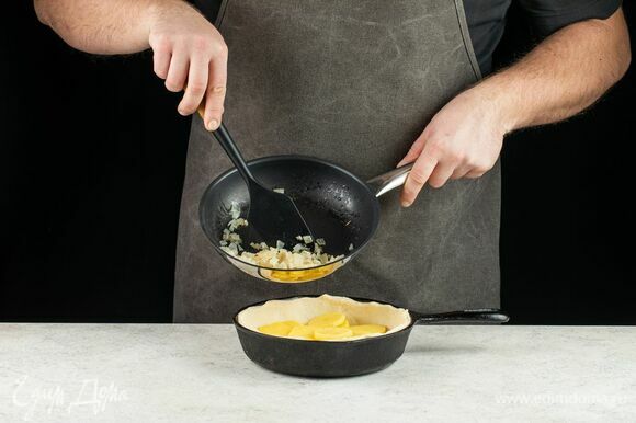 Форму для выпечки смажьте маслом. Тесто разделите на две части: одну побольше и вторую поменьше. Часть побольше раскатайте и поместите в форму для выпечки. Выложите слой картофеля на тесто.