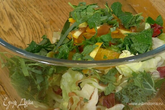 Салатные листья и нарезанный апельсин выложить в глубокую миску, полить готовой салатной заправкой, посыпать измельченной зеленью, добавить запеченный топинамбур и все перемешать.
