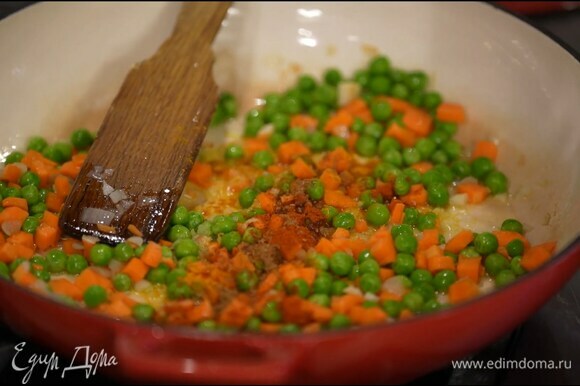 Морковь почистить, нарезать мелкими кубиками и отправить к луку с чесноком, добавить зеленый горошек, перемешать, всыпать куркуму, сладкую паприку, тмин, чили, посолить и еще раз перемешать.