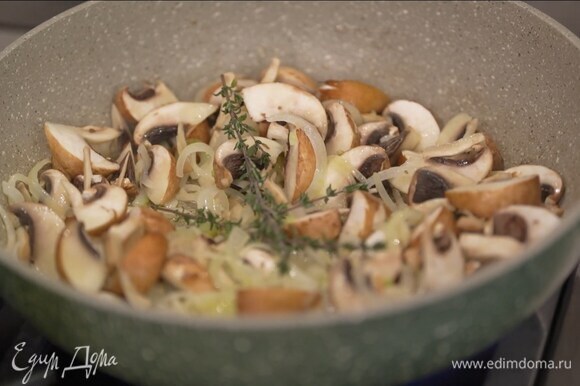 Разогреть в глубокой сковороде 1 ч. ложку сливочного и растительное масло и обжарить лук до прозрачности, затем добавить чеснок и грибы, немного посолить, выложить оставшиеся веточки тимьяна и, помешивая, обжарить.