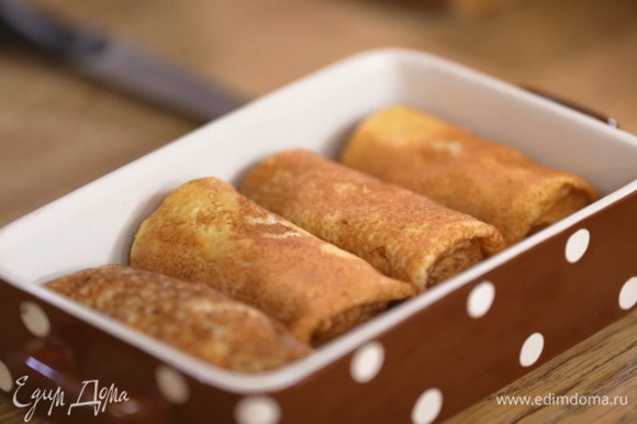 Завернуть начинку в блинчики, выложить их в небольшую жаропрочную форму, посыпать сыром и отправить в разогретую духовку на несколько минут, чтобы сыр расплавился.