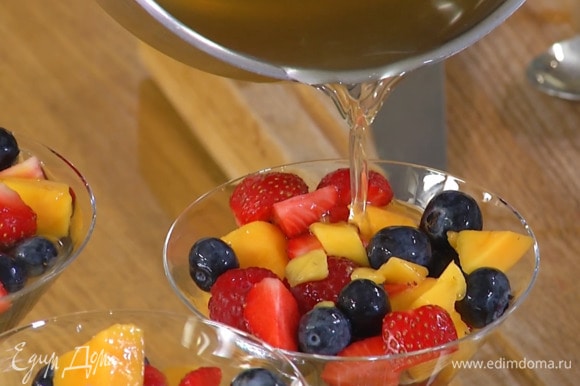 Разложить все ягоды и манго в прозрачные бокалы, залить травяным чаем и отправить десерт в холодильник до полного застывания.