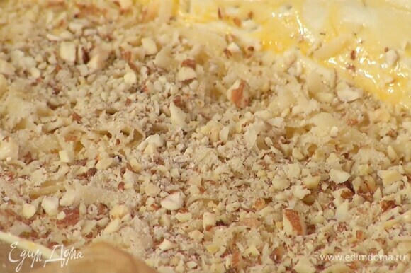 Марципан натереть на крупной терке и посыпать тесто, затем присыпать сверху измельченным миндалем.