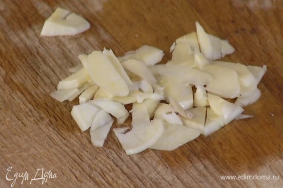 Чеснок почистить, нарезать небольшими кусочками и добавить к луку.